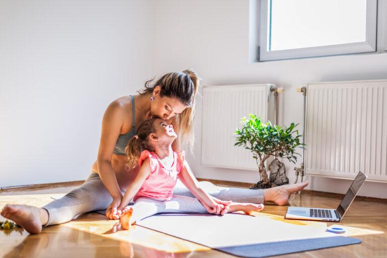 Pregnant mother practicing yoga with daughter at home