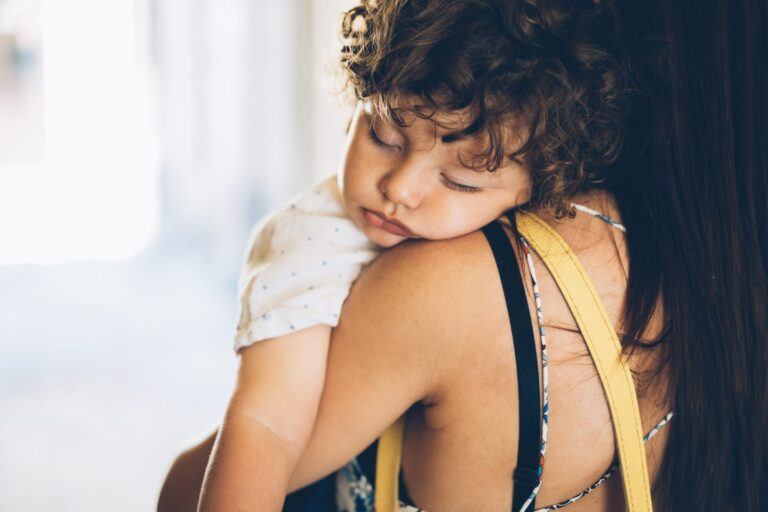 mom holding a sleeping toddler - two naps to one