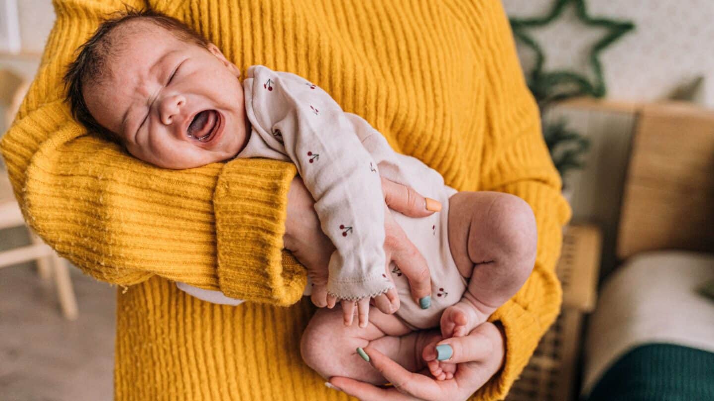 Mother holding crying baby with colic but taking probiotics for colic might help