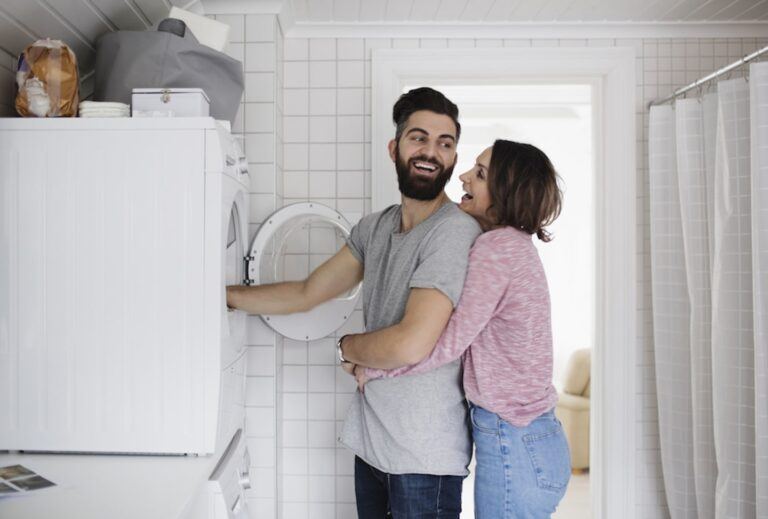 woman hugging partner as he does laundry