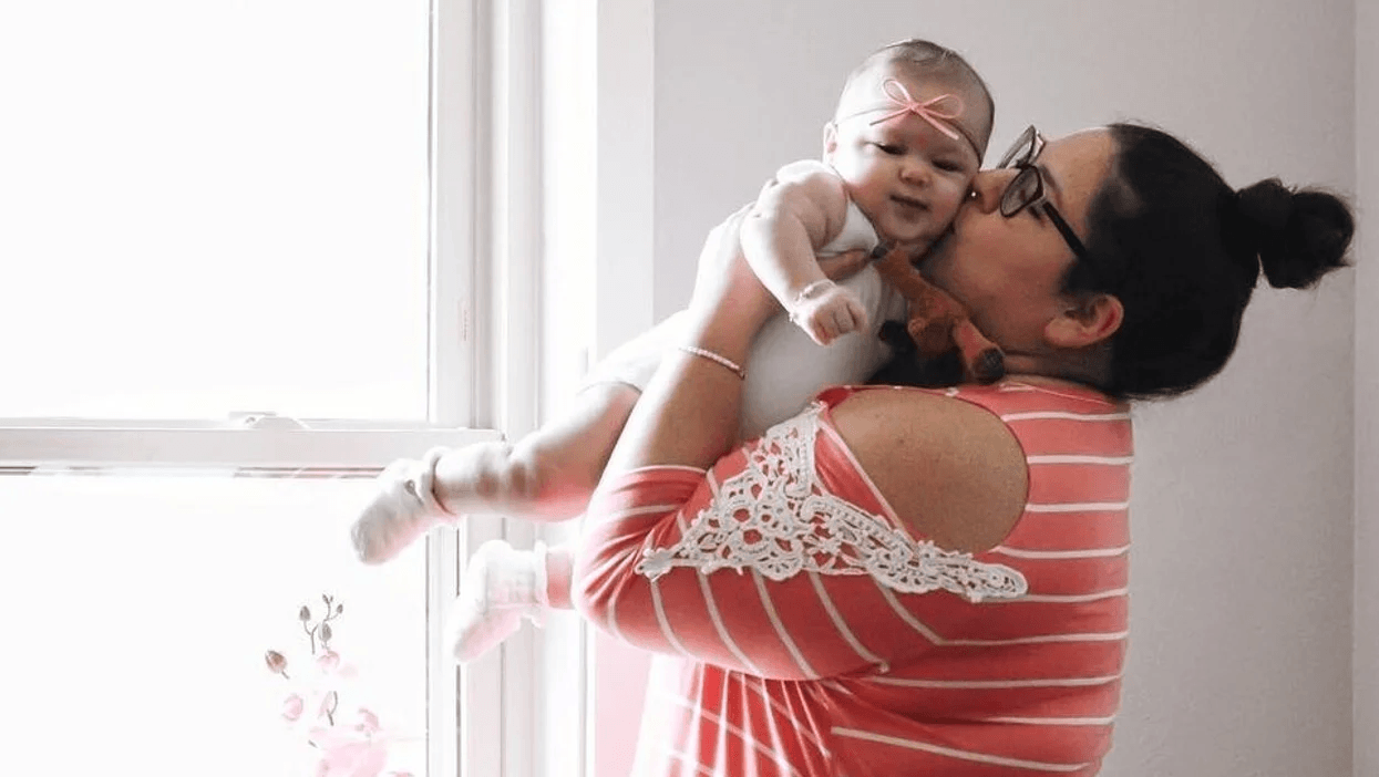 mom holding baby and kissing its cheek