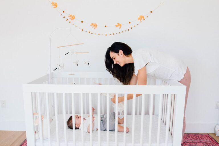 mom playing with baby, who is in the crib