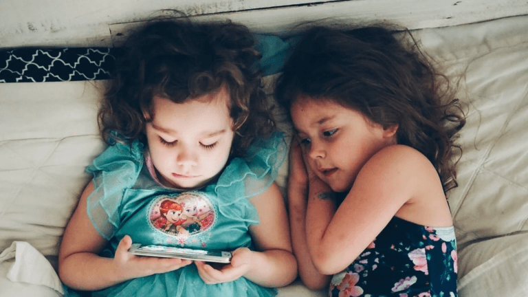 two siblings watching a phone screen