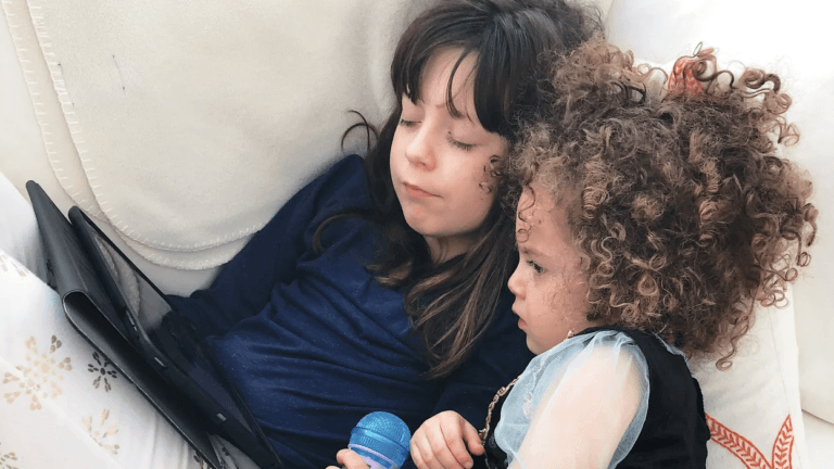 two kids huddled together watching a tablet