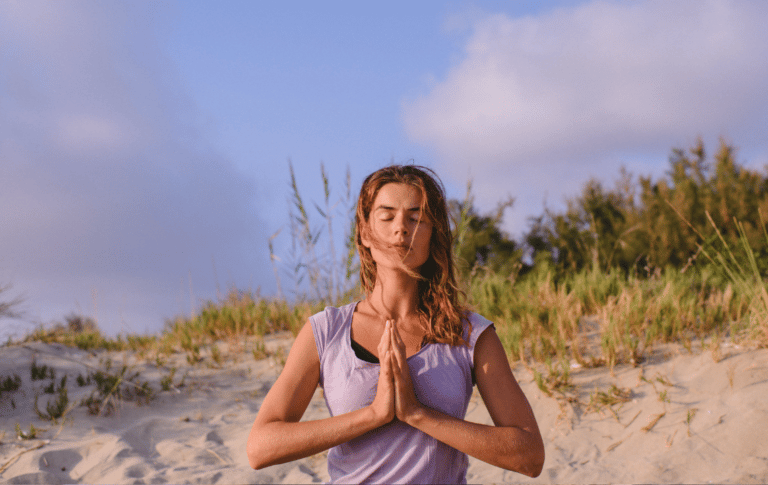 woman meditating on the beach