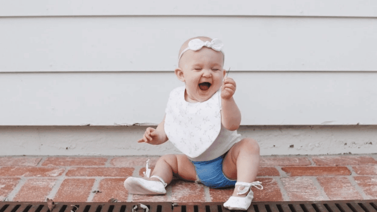 baby laughing at a piece of grass- july babies