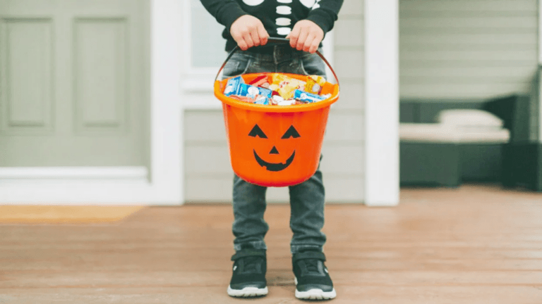 little boy holding a bucket of halloween candy