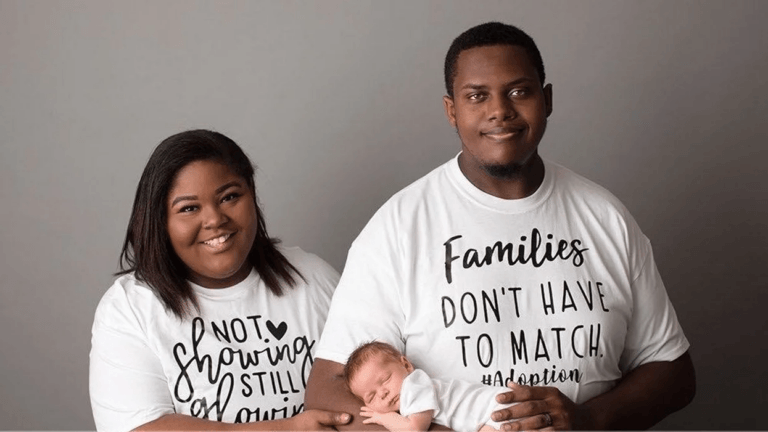 two parents holding adopted baby