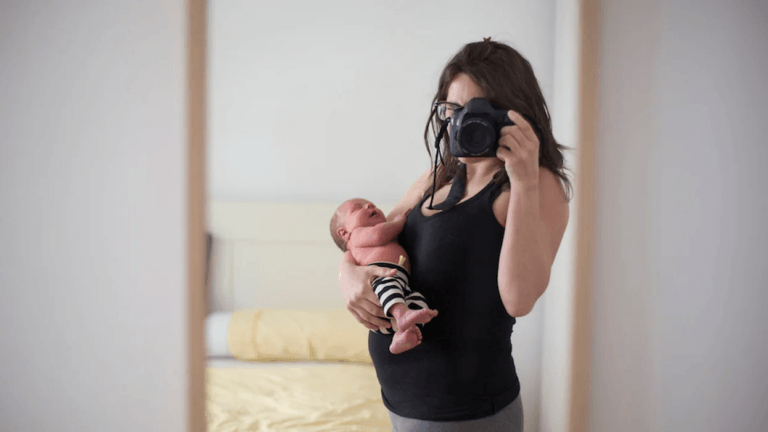 new mom taking a selfie holding newborn baby, ready to rock the 4th trimester