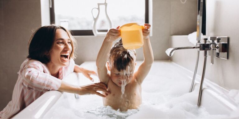 mom playing at bathtime with son - how often should I bathe my child