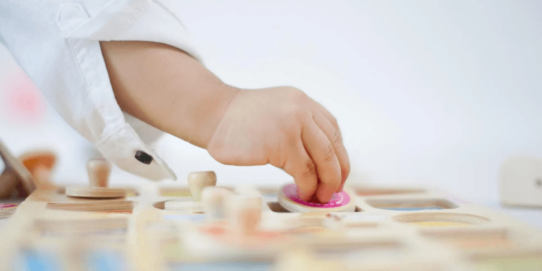 toddler hand playing with a wooden puzzle