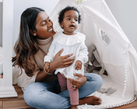 mother sits with toddler child near tent