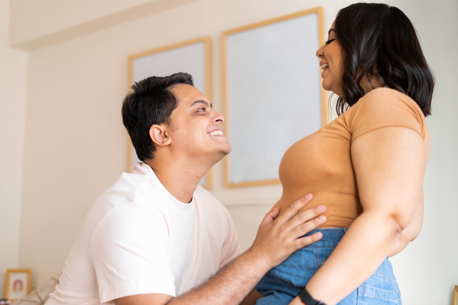 couple smiling over pregnancy announcement from creative ways to tell your partner youre pregnant Motherly