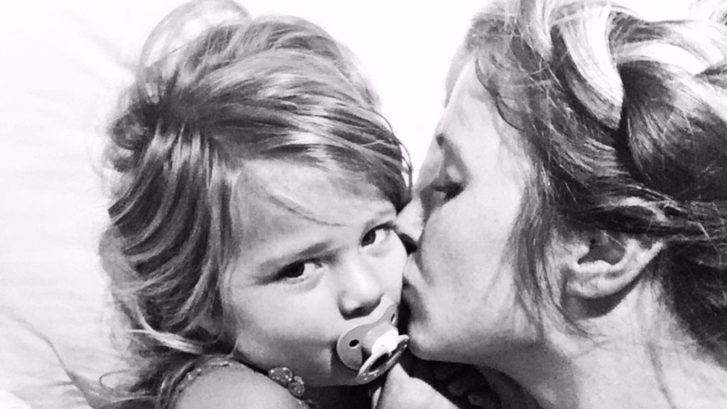 mom kissing daughter on the cheek