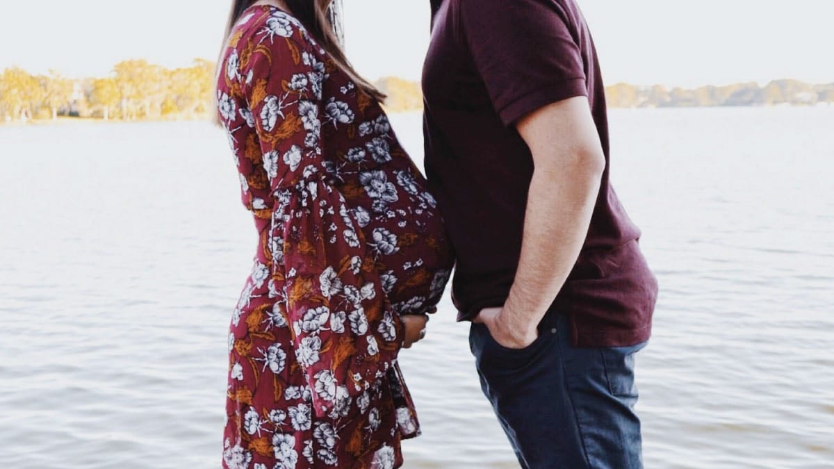 pregnant woman pressing belly up against partner's