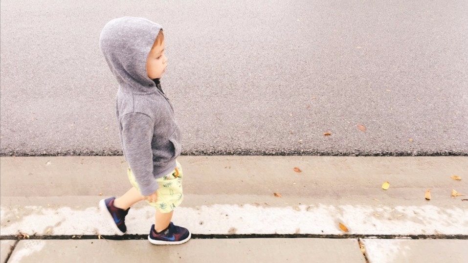 toddler boy walking on a sidewalk