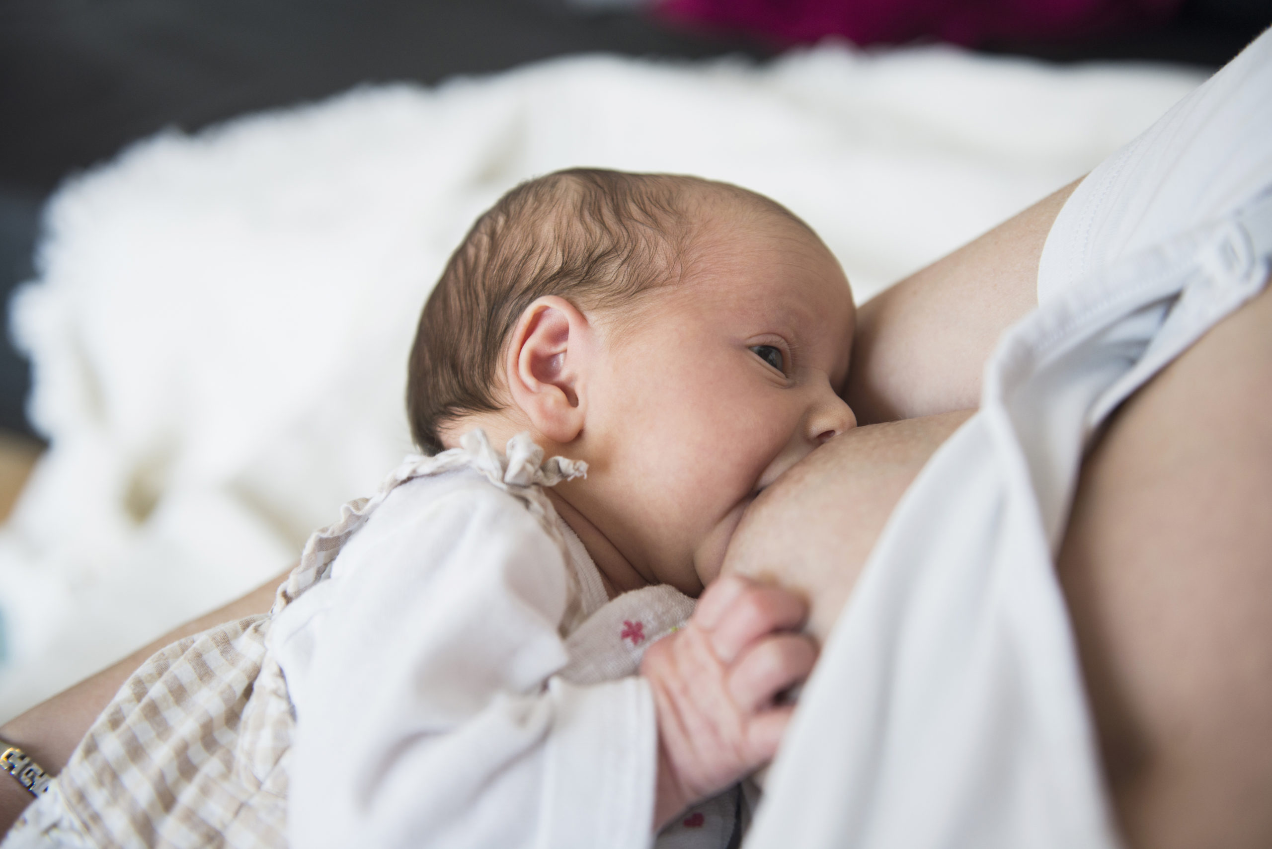 a baby breastfeeding a woman