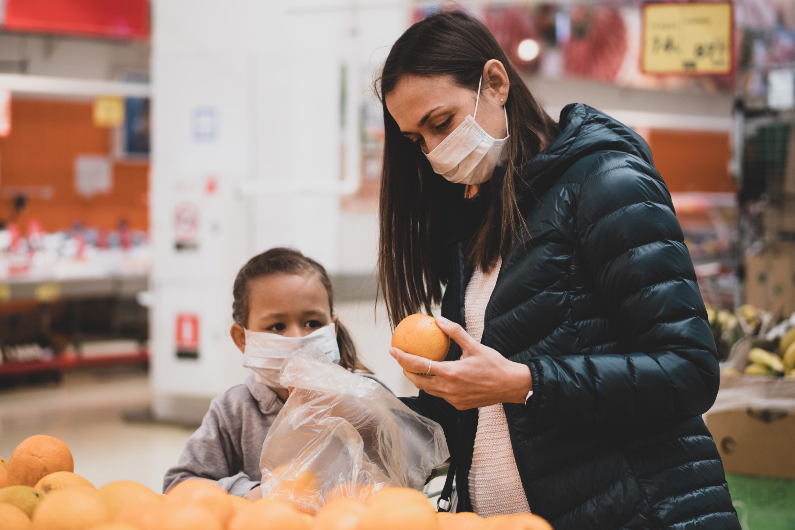 mom grocery shopping with child, both wearing massk