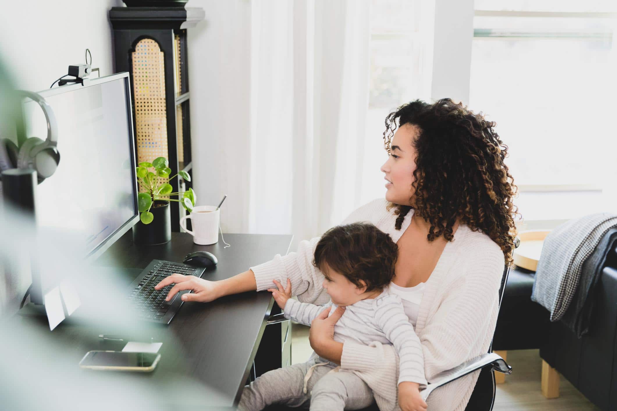 child sitting on moms lap while she works