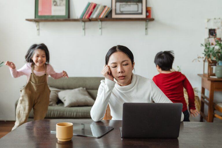 mom working with kids playing behind her