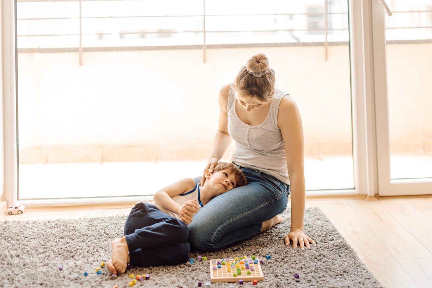 mother sitting with child's head in lap with discarded puzzle pieces on the floor- kids diagnosed with autism