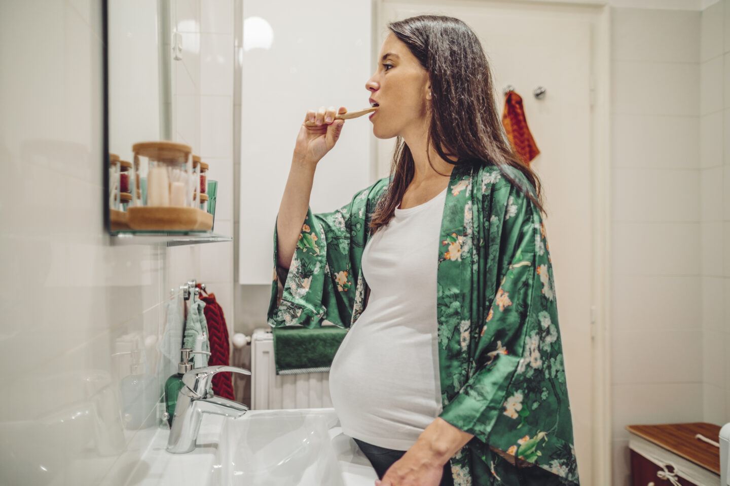 gingivitis in pregnancy: pregnant woman brushing her teeth in the bathroom