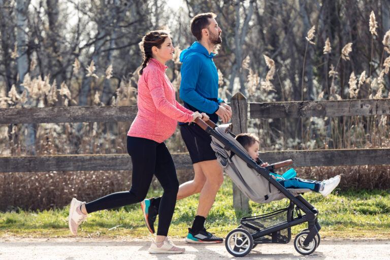 heart health in pregnancy: pregnant woman jogging while pushing stroller with partner