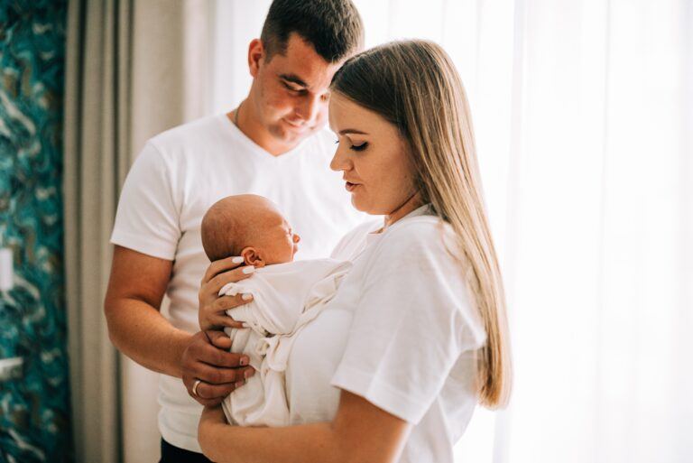 mother and father holding newborn baby at home - signs of postpartum depression