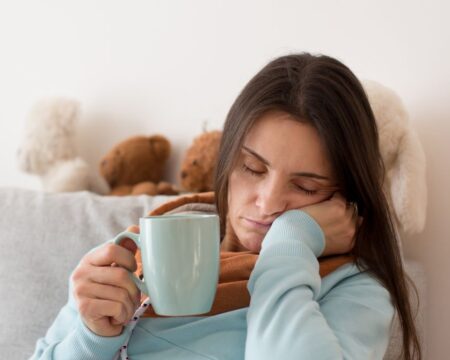 tired mom falling asleep while holding coffee cup- daylight saving time