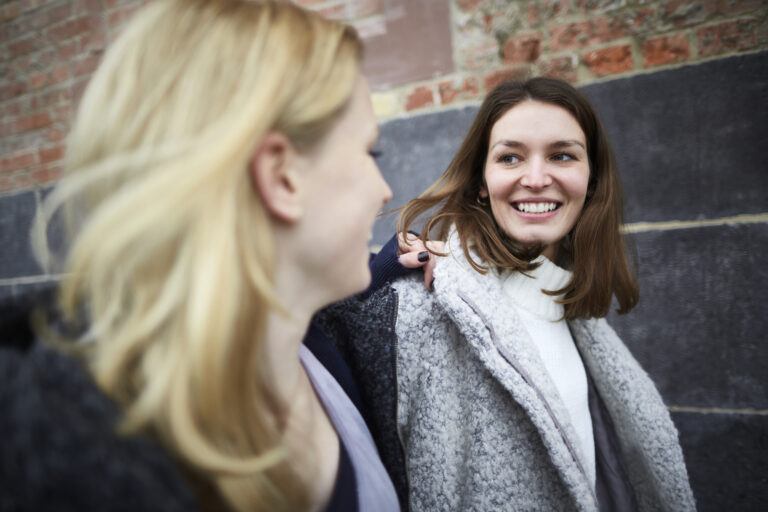 what not to say to a pregnant woman: two smiling women walking down the street