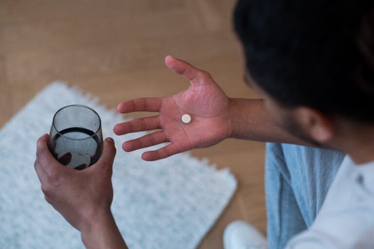 male birth control: man holding pill in one hand and glass of water in other hand