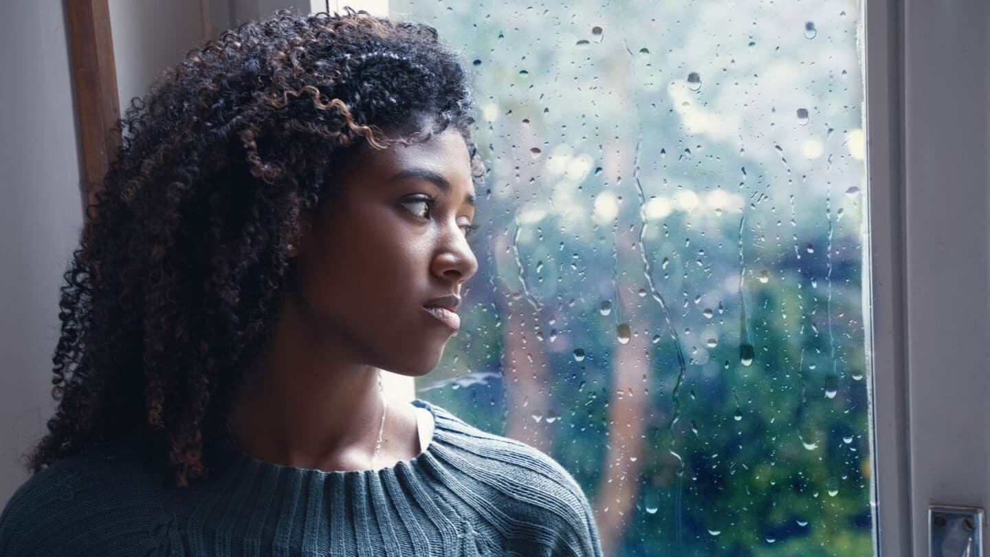 sad woman looking outside a rainy window