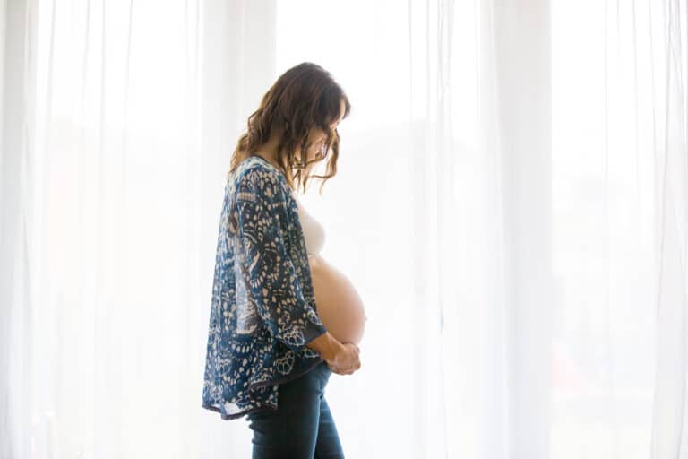 Portrait of beautiful pregnant woman and her cute child, isolated image on white background, back lit