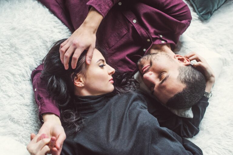 man and woman laying opposite of each other in a bed