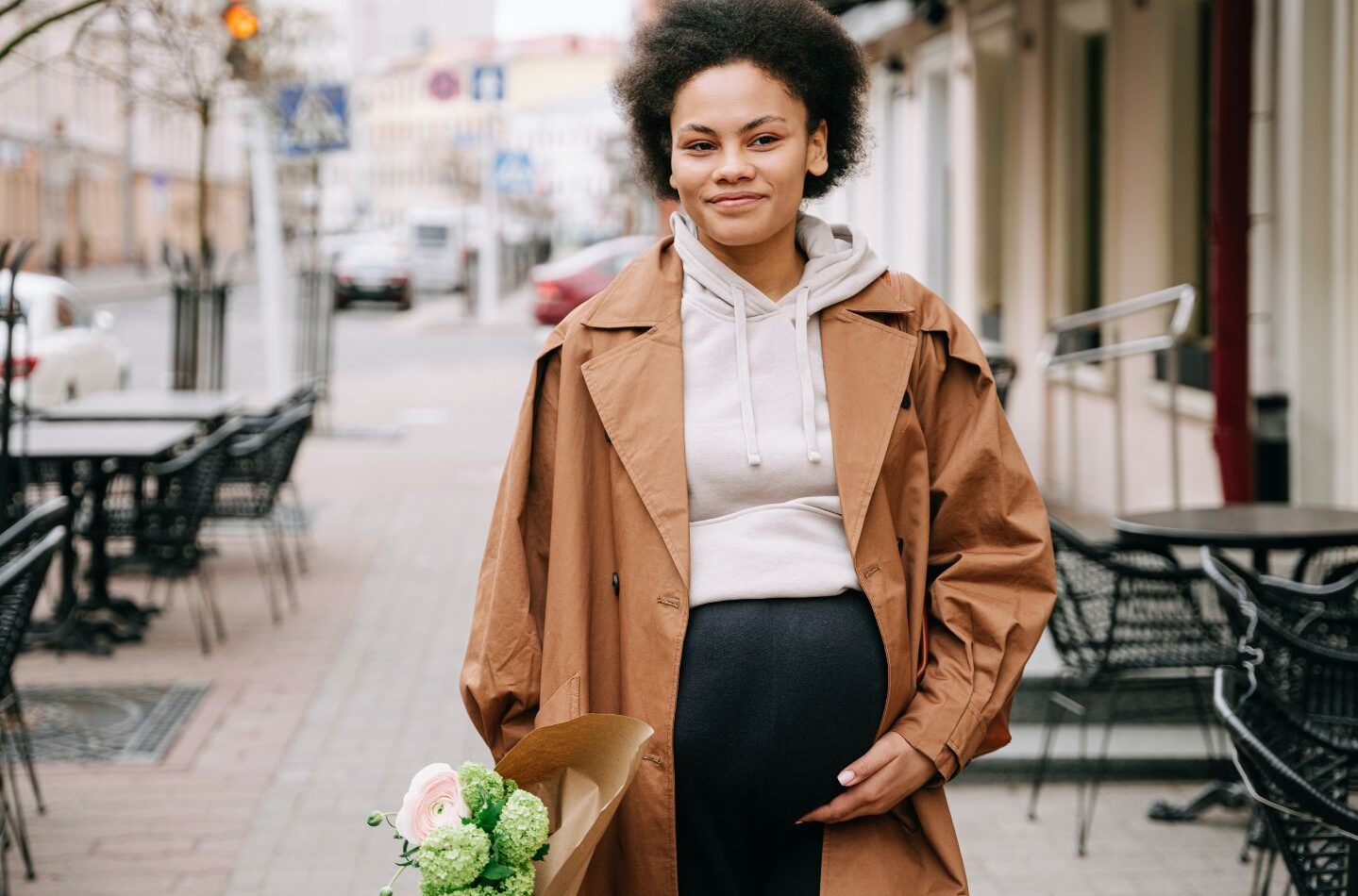 pregnant woman walking in city holding flowers