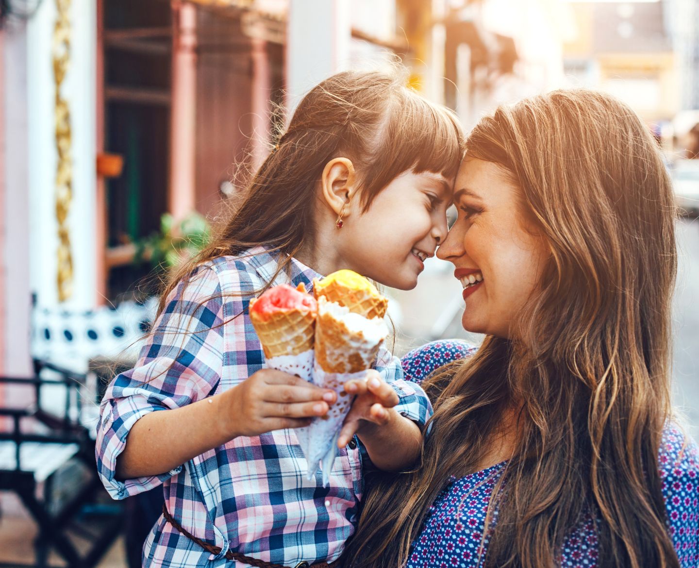 mom and daughter with foreheads pressed against each other eating ice cream