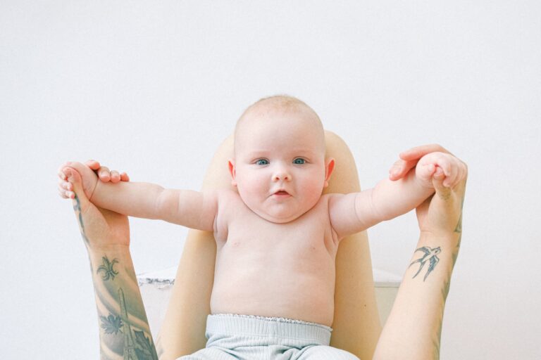 tattood mom holding baby's hands