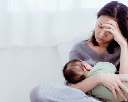 stressed out mom breastfeeding with her head in her hand