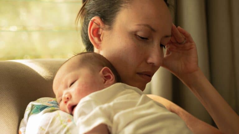 tired mom holding newborn while on parental leave