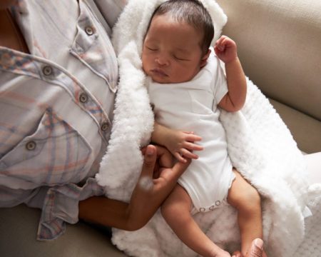 baby sleeping in mothers arms at home walking then sitting is one way how to get a baby to sleep