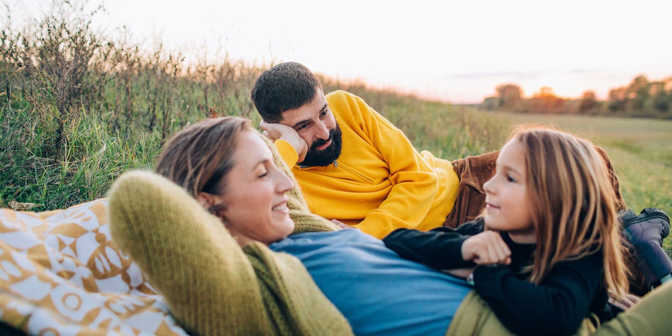 family laying together in a field, on a family fall vacation