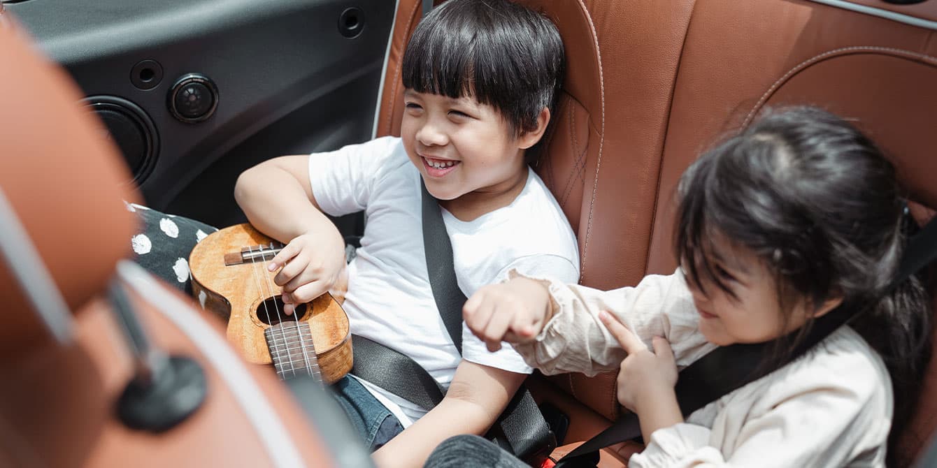 kids sitting in backseat of car playing guitar, road trip activities