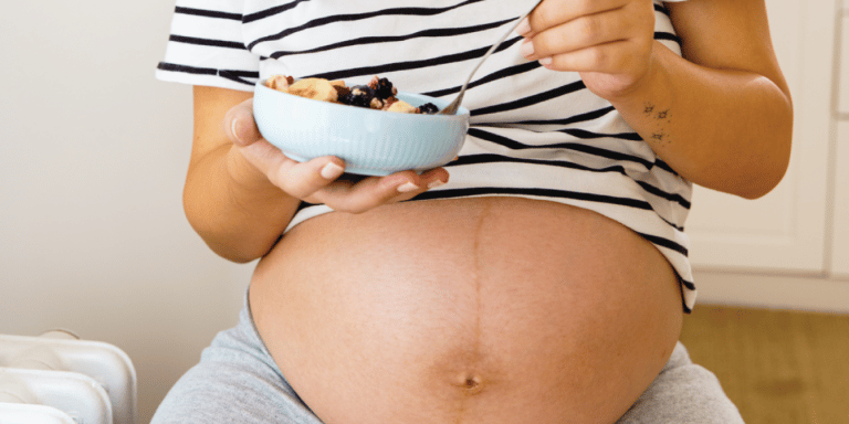 pregnant womans belly with a breakfast bowl in front of it - best foods for pregnancy