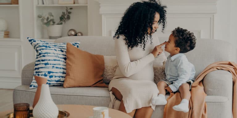 pregnant mom and son sitting on the sofa talking, raising sons