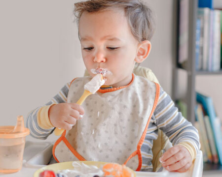 baby eating ripe berries with yogurt