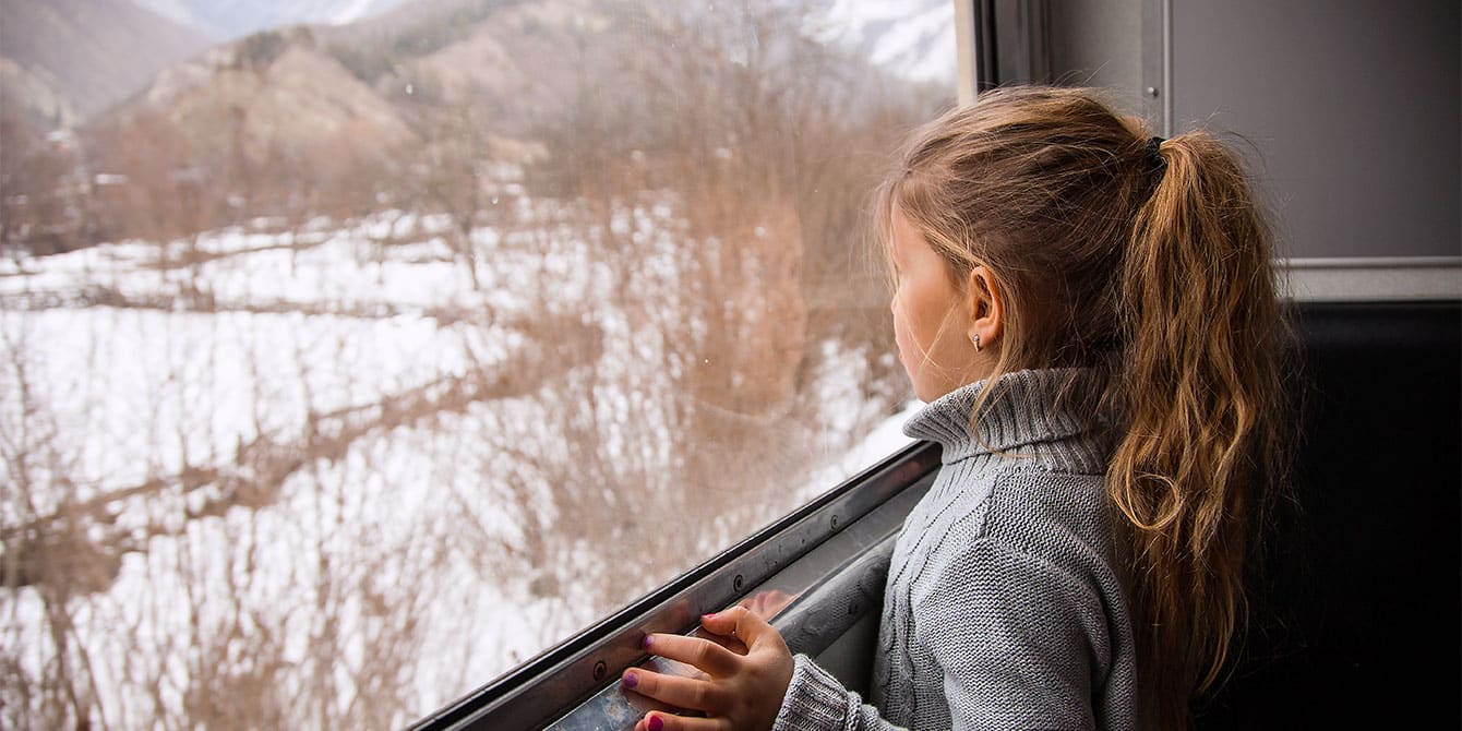 little girl in a sweater looking out train window - holiday train rides