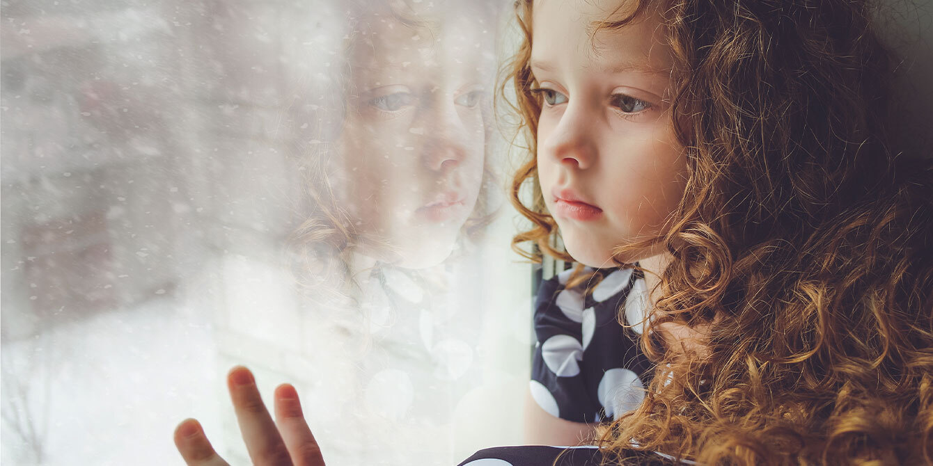 little girl looking out at the snow thru the window - seasonal affective disorder