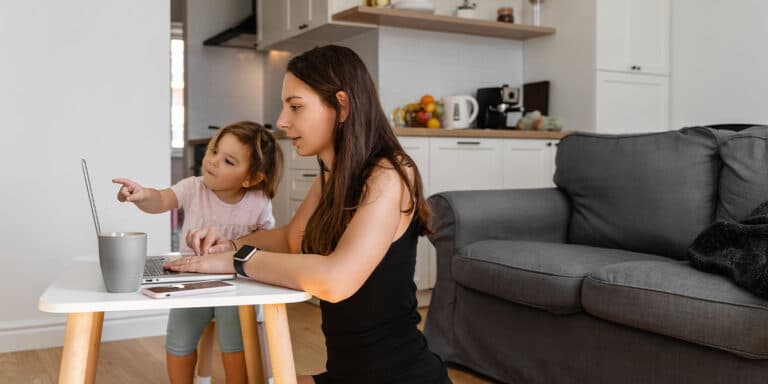 mom looking at options for online therapy on computer next to her child