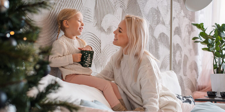 mom and daughter laughing on the couch on christmas Motherly