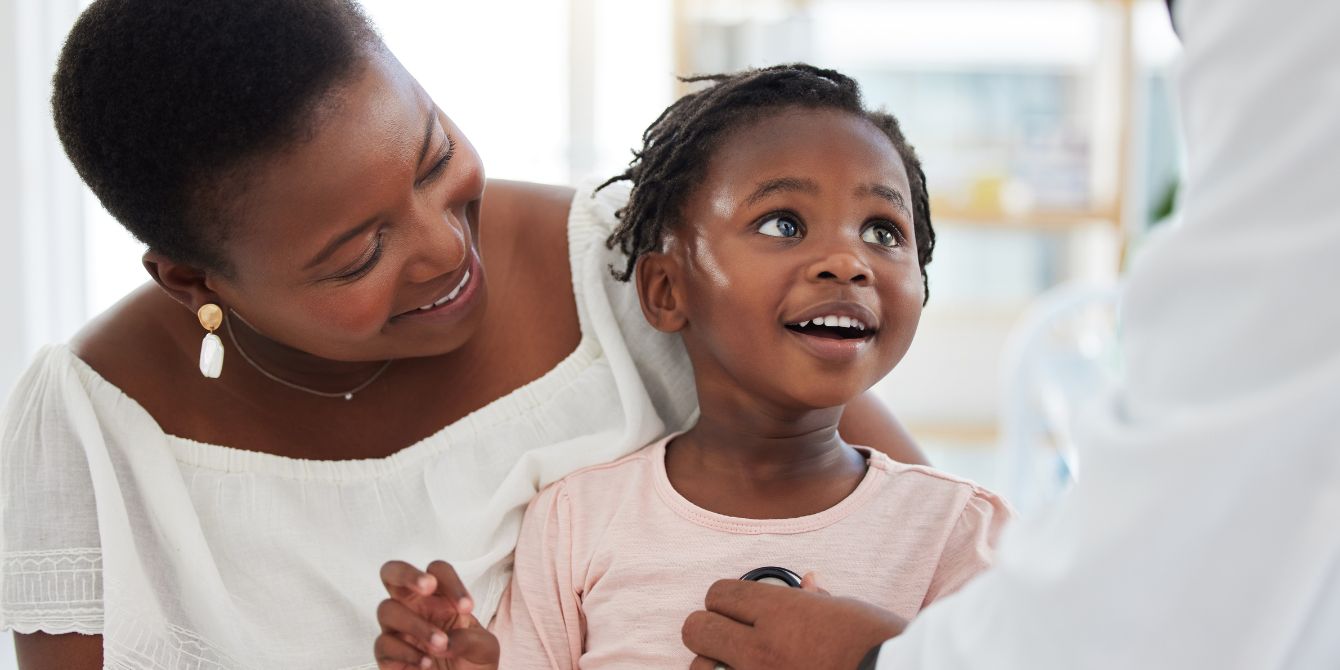 Mom holding toddler during doctor visit - best hospitals